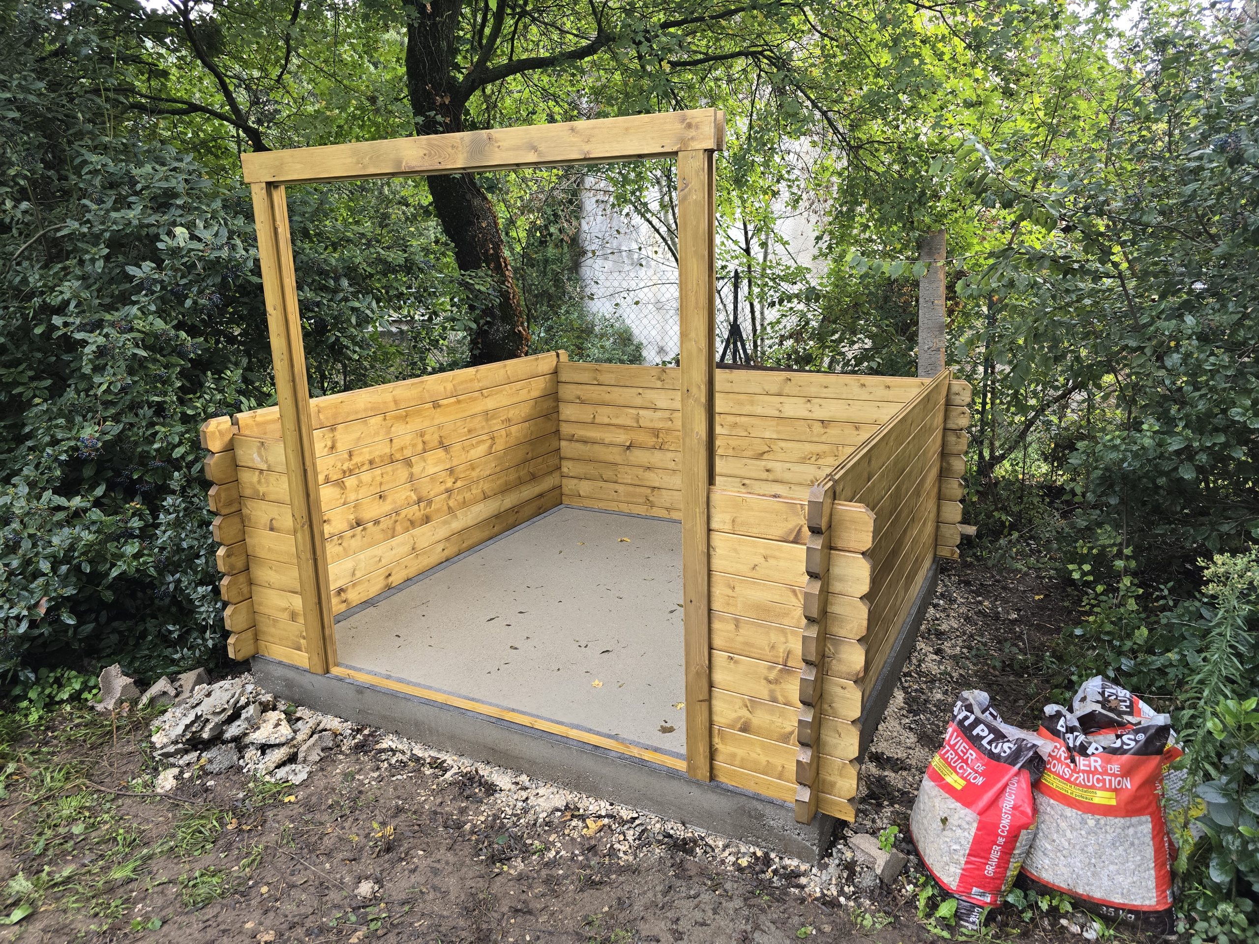 Montage d'un abri de jardin en bois : cadre de porte fixé et partie basse des madriers posés