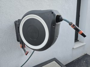 Dévidoir automatique mural Gardena RollUp 25m fixé au mur de la maison — tuyau déroulé dans le jardin à Auriol
