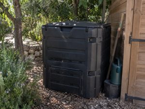Composteur noir de 600 litres installé à l'ombre, contre l'abri de jardin