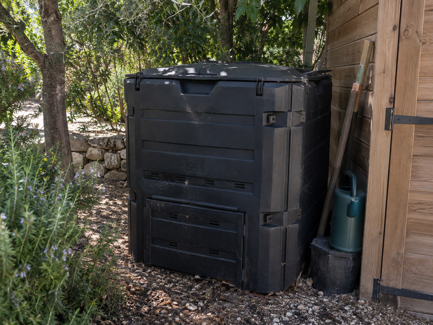 Composteur noir de 600 litres installé à l'ombre, contre l'abri de jardin