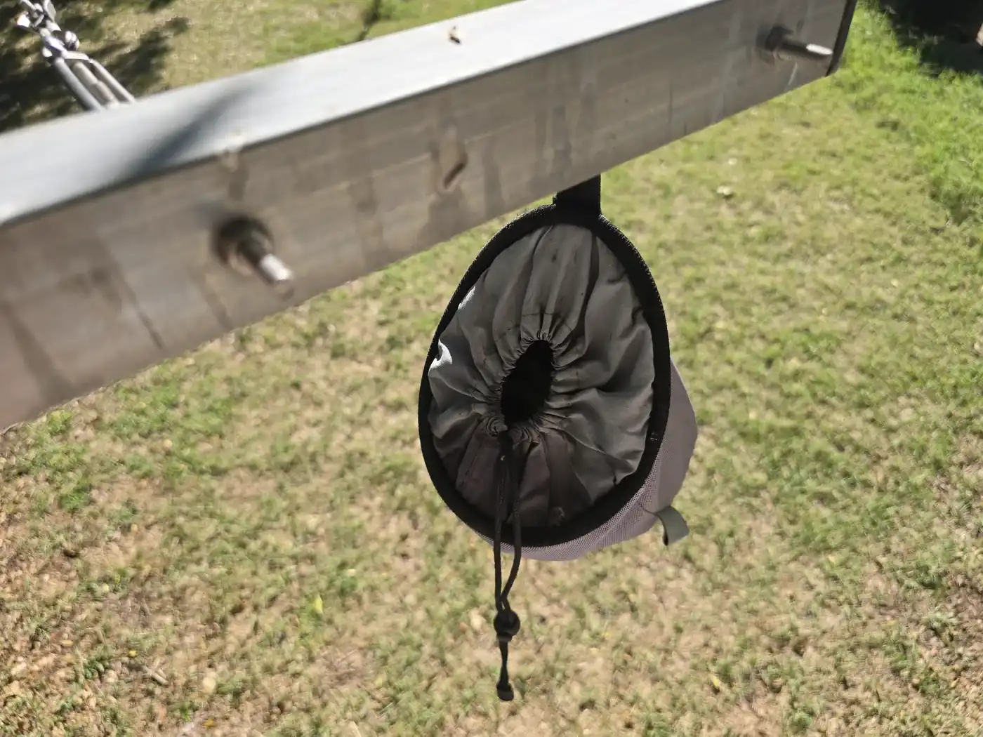 Sac à pinces à linge gris suspendu à un étendoir, avec son ouverture à cordon